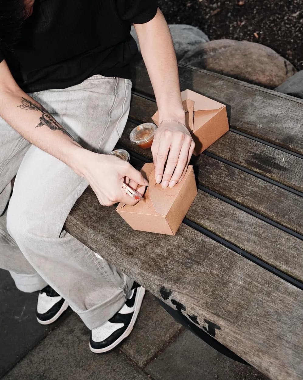 Opening a box of bánh tráng on a bench outside