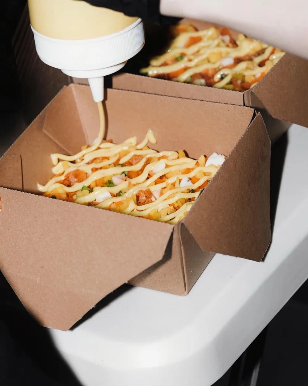 Sauce drizzled over a fresh box of bánh tráng trộn